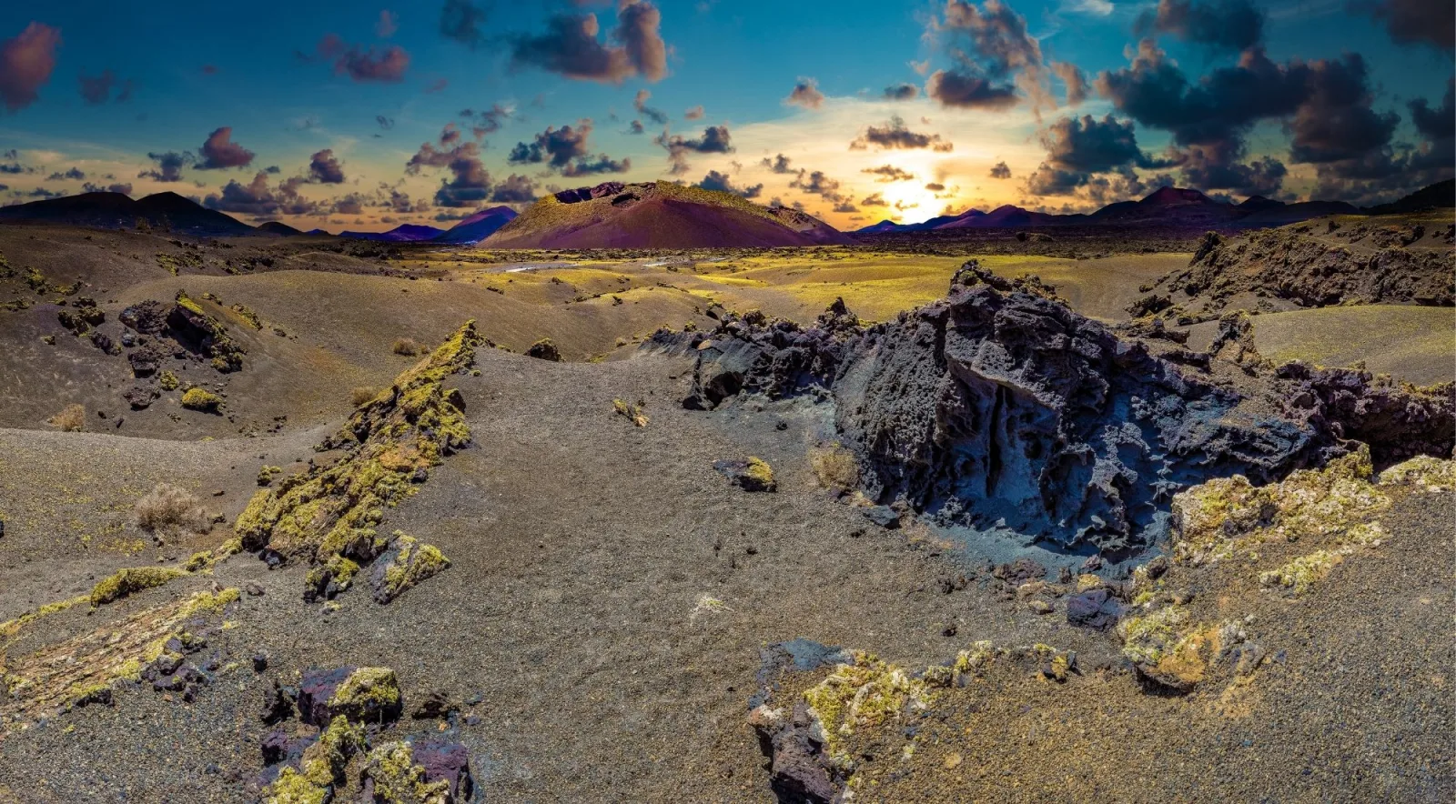 Sunset over the crater field of Lanzarote's Fire Mountains, with broken lava rock in the foreground