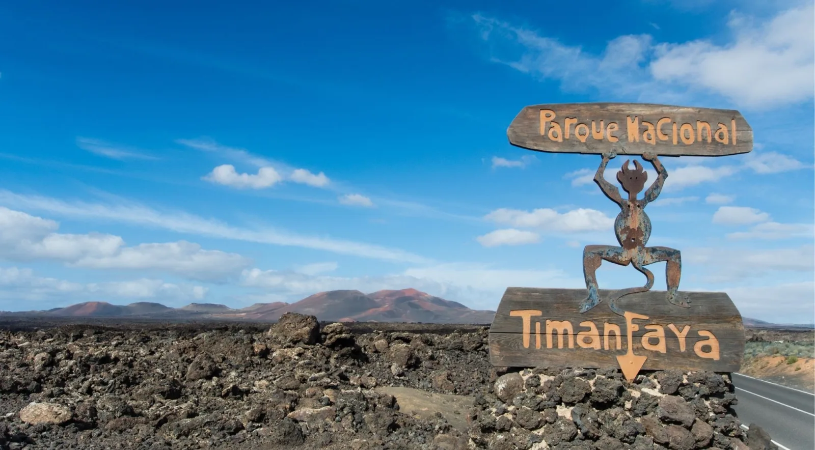 The wooden Parque Nacional Timanfaya entrance sign with César Manrique's wrought-iron devil emblem