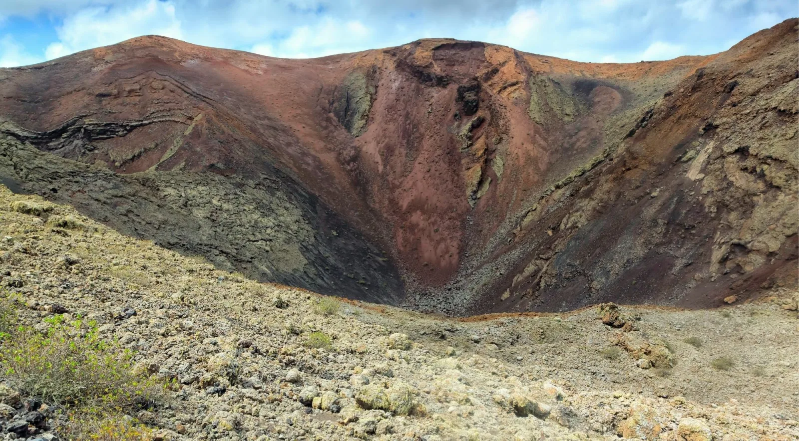 Inside a volcanic crater, its walls banded in red, ochre and grey ash
