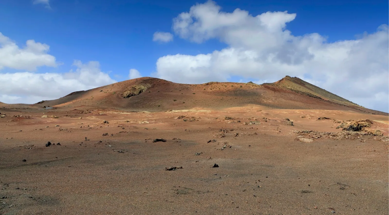 The LZ-67 road running dead straight through black lava fields towards red hills and a white village