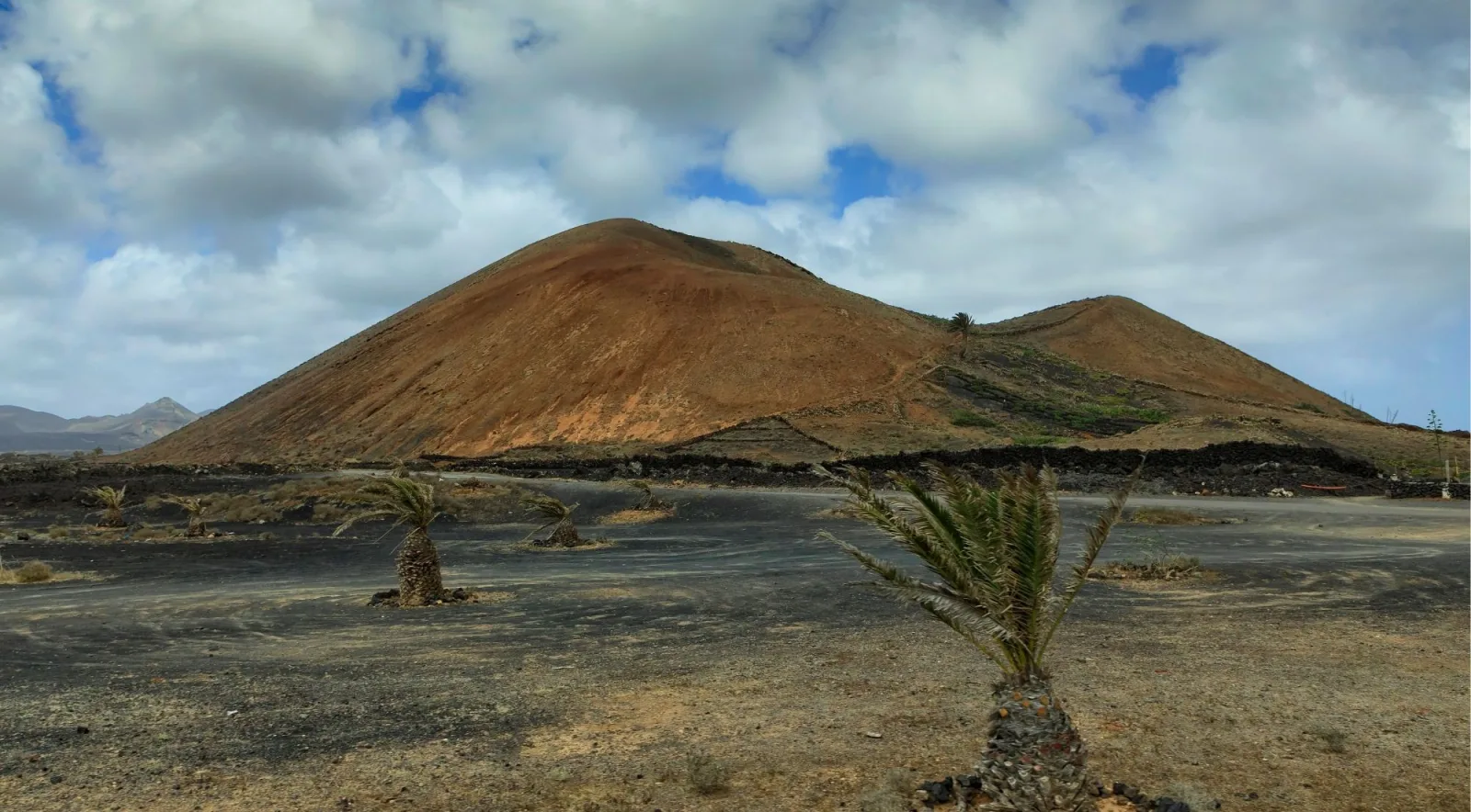 El Golfo's green lagoon beside a black sand beach and eroded red cliffs on the Atlantic coast