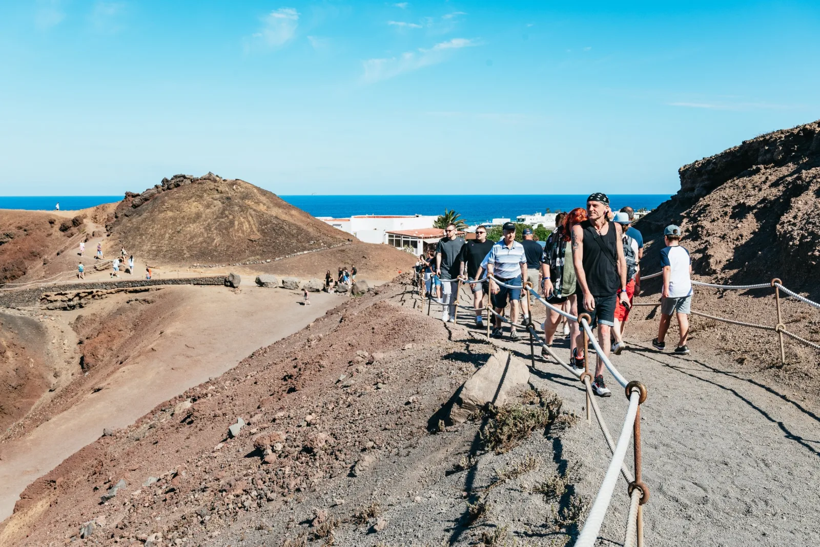 Visitors walking the railed path down from the Islote de Hilario viewpoint