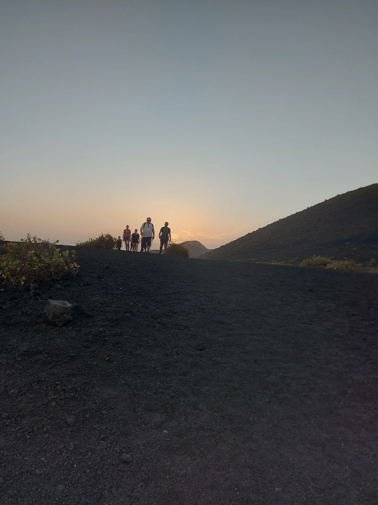Walkers approaching a dark cone in the flat light of dusk