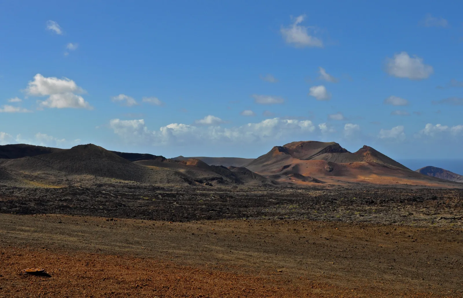 Low red-black cones along the horizon across the flat lava plain