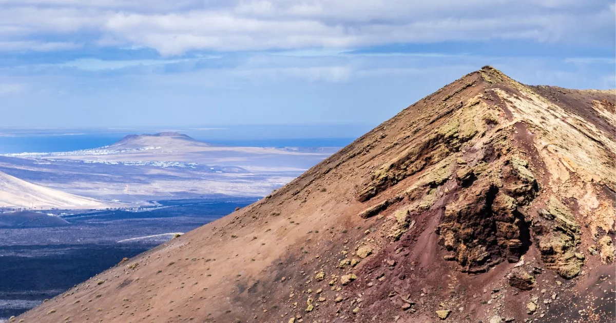 View from a Lanzarote volcanic cone towards a coastal resort town in the distance